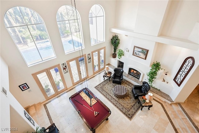 living area featuring visible vents, french doors, a glass covered fireplace, and a towering ceiling