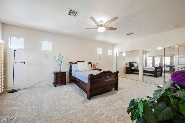 bedroom with two closets, ceiling fan, and light colored carpet