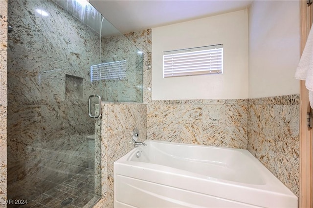 bathroom featuring a shower stall and a bath