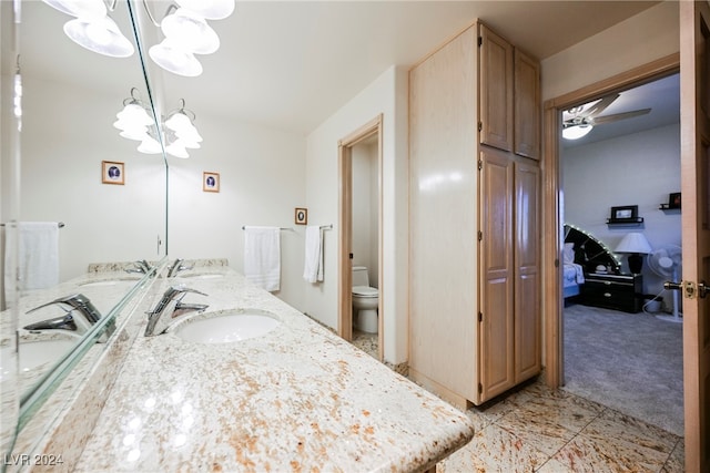 bathroom with tile patterned flooring, vanity, toilet, and ceiling fan with notable chandelier