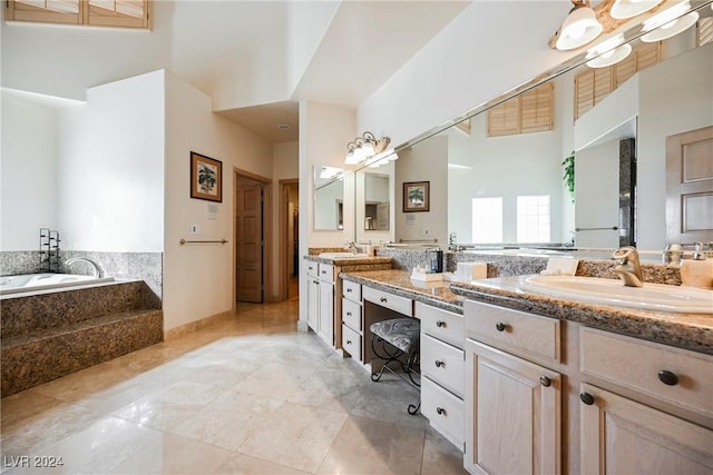 bathroom featuring a garden tub, double vanity, a sink, and a towering ceiling