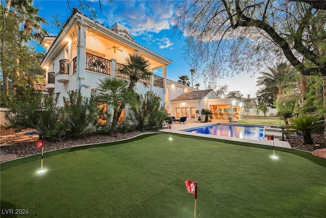 back of house featuring a patio area, an outdoor pool, a balcony, and ceiling fan