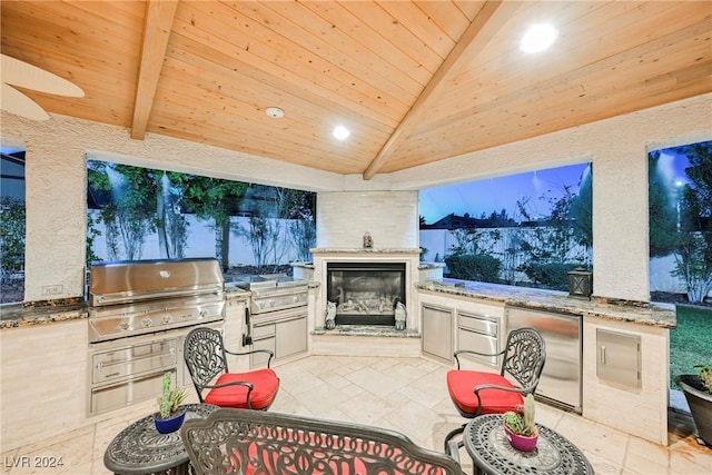 view of patio / terrace with grilling area, exterior kitchen, and a glass covered fireplace