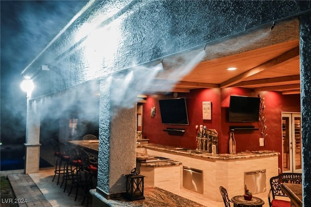 bar with indoor wet bar and beam ceiling