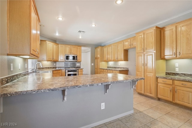 kitchen with a kitchen bar, light brown cabinetry, sink, and stainless steel appliances