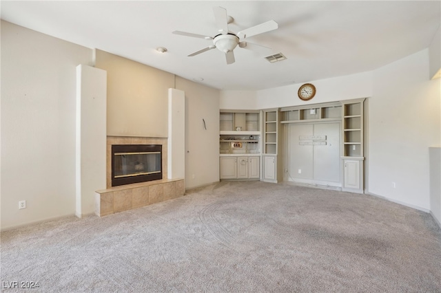 unfurnished living room with ceiling fan, light colored carpet, and a tile fireplace