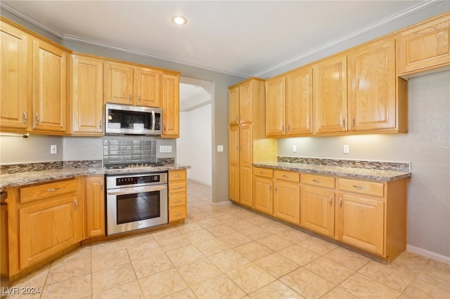 kitchen with appliances with stainless steel finishes, stone counters, and ornamental molding