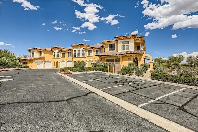 exterior space featuring a tiled roof, stucco siding, uncovered parking, and a residential view