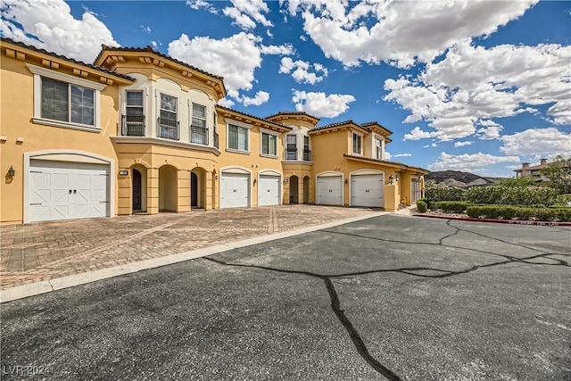 view of front of property with driveway, stucco siding, a tile roof, and an attached garage
