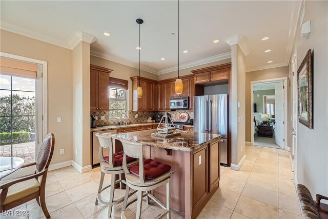 kitchen with stone counters, a sink, tasteful backsplash, appliances with stainless steel finishes, and a center island