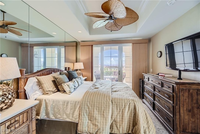 bedroom with access to exterior, multiple windows, and a raised ceiling