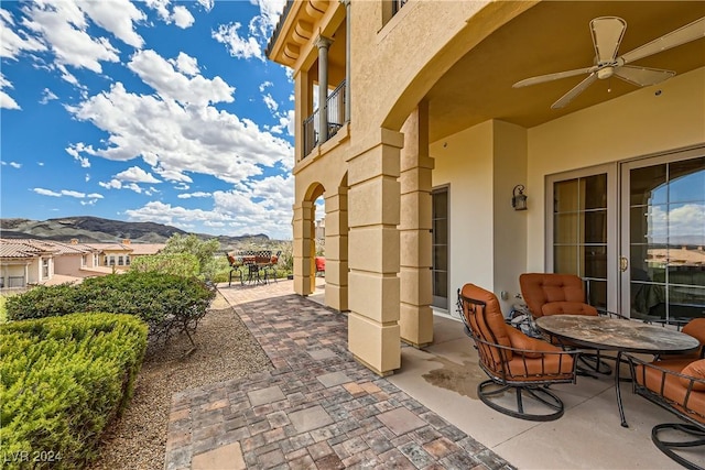 view of patio / terrace featuring a mountain view, outdoor dining space, and a ceiling fan