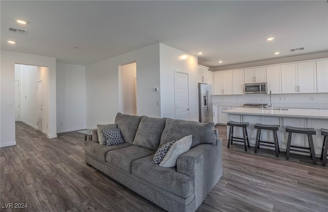 living room with dark hardwood / wood-style floors and sink