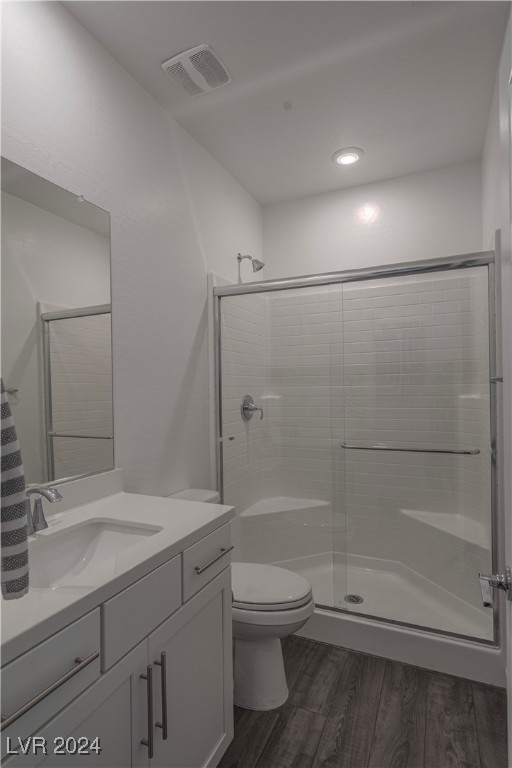 bathroom featuring hardwood / wood-style floors, vanity, toilet, and a shower with door