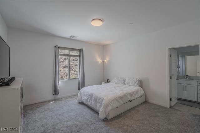 carpeted bedroom with ensuite bath and sink