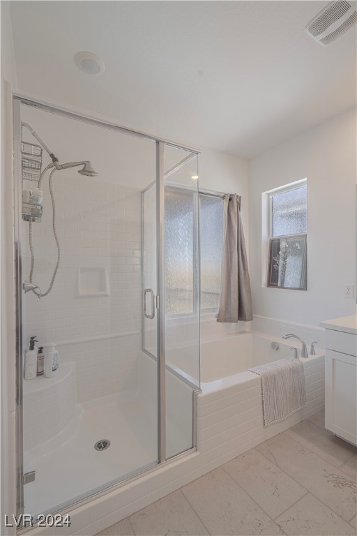 bathroom with vanity and shower with separate bathtub