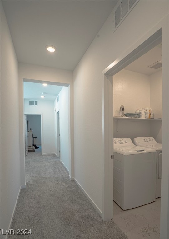 corridor featuring light colored carpet and separate washer and dryer