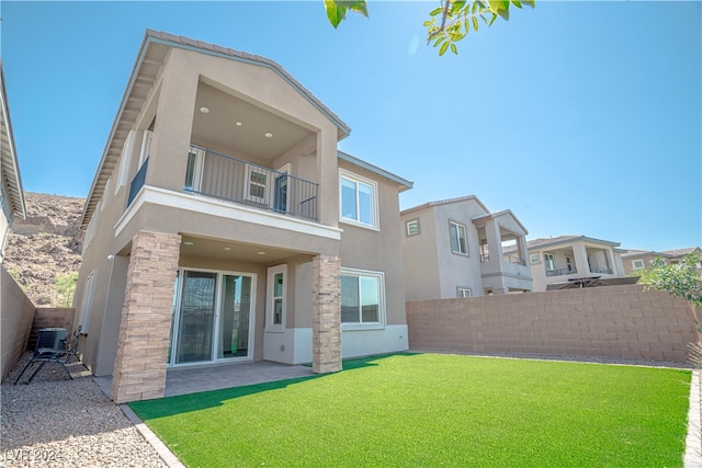 back of house with a balcony, central AC, and a lawn