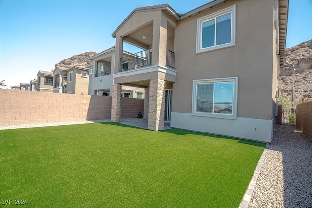 rear view of house featuring a lawn and a balcony