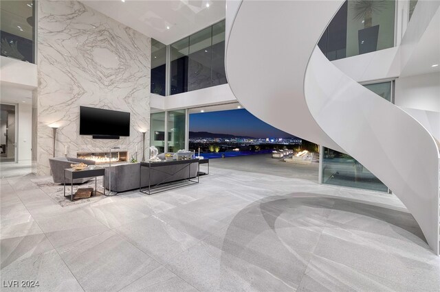 living area with a towering ceiling, stone wall, and a wall of windows