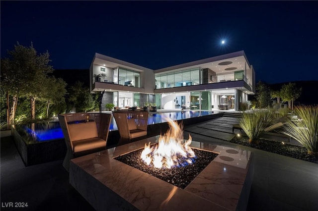 back of house at twilight with a fire pit and an outdoor pool