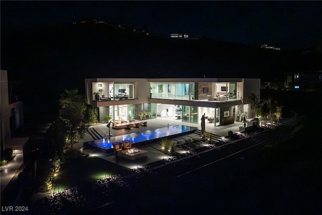 back house at night with a swimming pool and a balcony