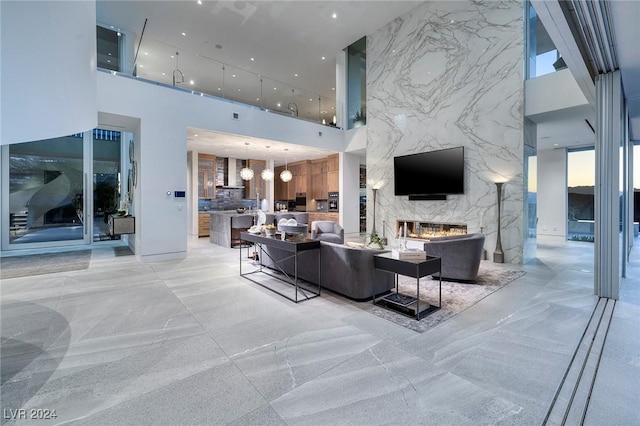 living area with stone wall, recessed lighting, an accent wall, a high ceiling, and a fireplace