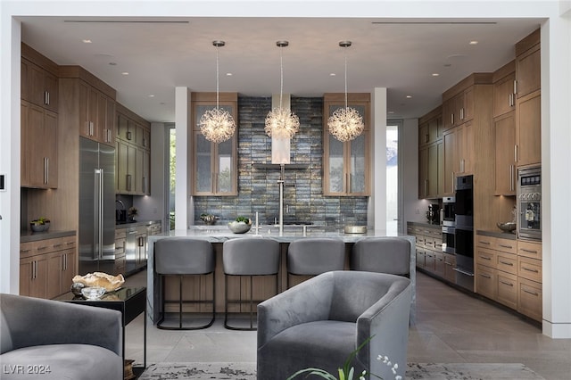 kitchen with tasteful backsplash, appliances with stainless steel finishes, sink, a kitchen bar, and decorative light fixtures