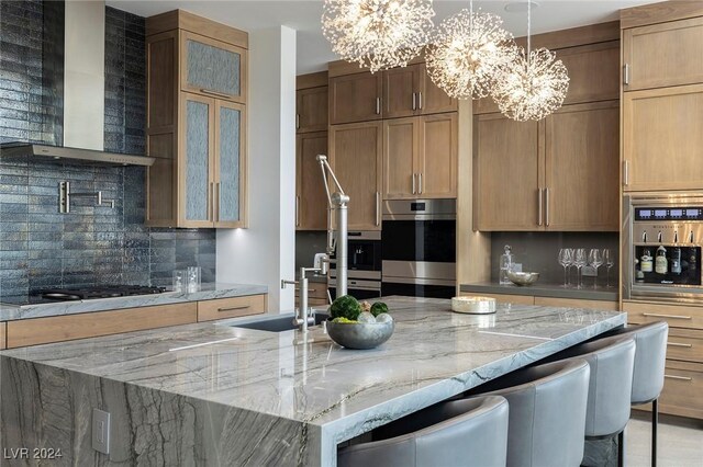 kitchen featuring gas stovetop, stainless steel double oven, wall chimney exhaust hood, backsplash, and light stone countertops