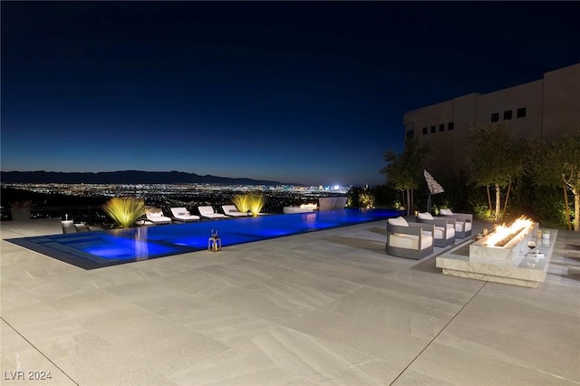 pool at twilight with an infinity pool and a patio area