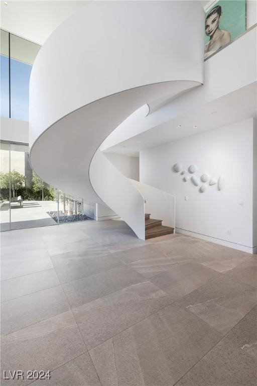 interior space with stairs, a towering ceiling, and floor to ceiling windows