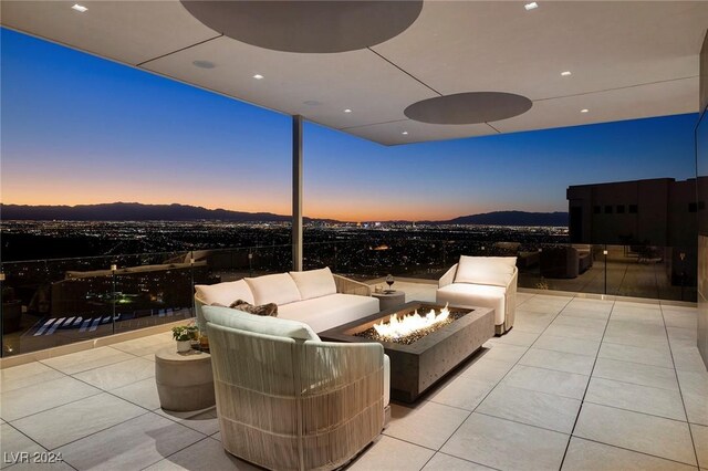 patio terrace at dusk featuring a mountain view and an outdoor living space with a fire pit