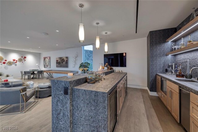 kitchen with a spacious island, light hardwood / wood-style flooring, sink, and decorative light fixtures