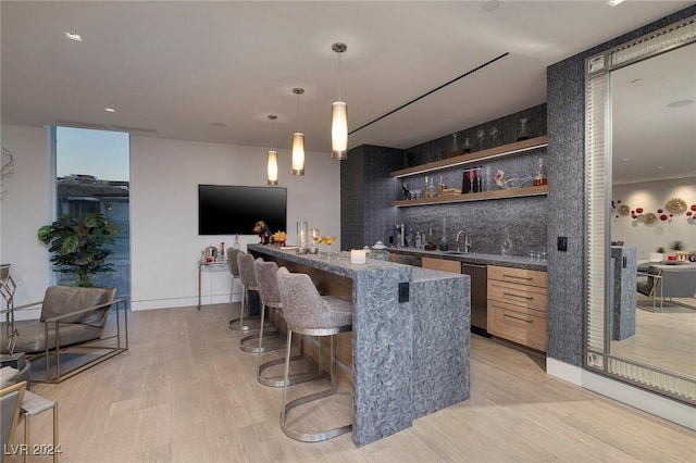 bar featuring tasteful backsplash, baseboards, hanging light fixtures, light wood-style floors, and indoor wet bar