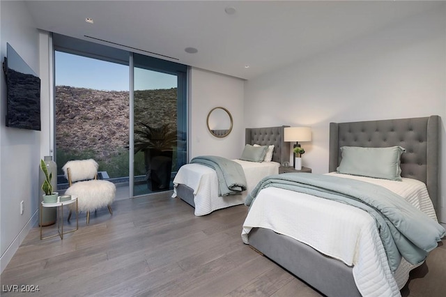 bedroom featuring access to exterior, a wall of windows, and wood finished floors