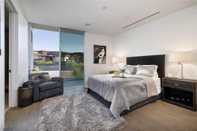 bedroom with light wood-type flooring, a wall of windows, and access to exterior