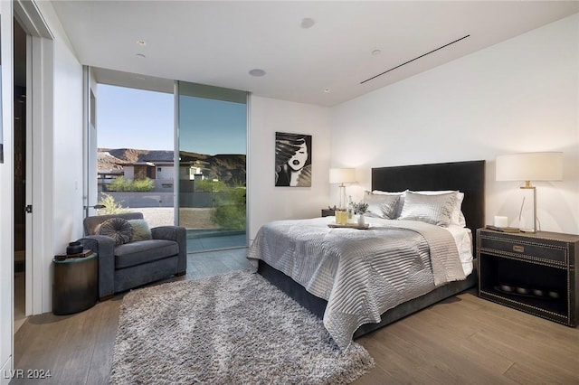 bedroom featuring access to outside, a wall of windows, and wood finished floors