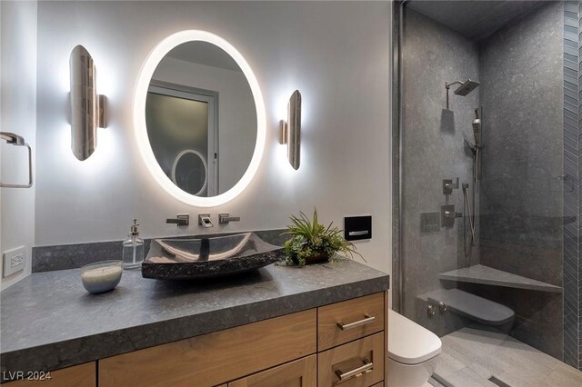 bathroom with vanity, toilet, and tiled shower