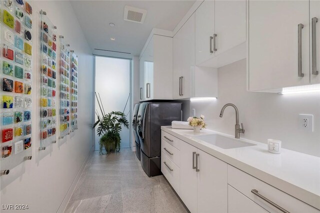 washroom featuring cabinets, sink, and washing machine and clothes dryer