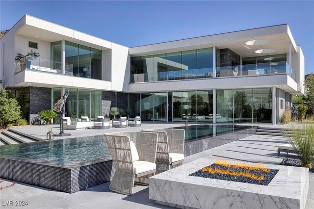 rear view of house featuring a balcony, an outdoor fire pit, and a patio area