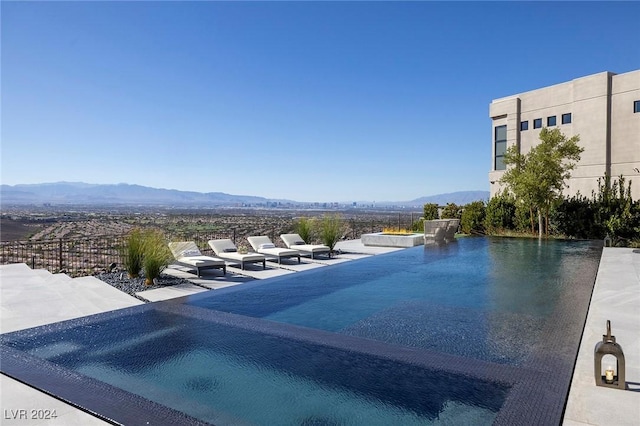 view of swimming pool featuring a patio area, fence, and a mountain view