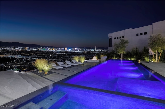 pool at night with an in ground hot tub