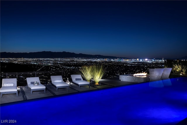 pool at twilight featuring a patio area and a mountain view