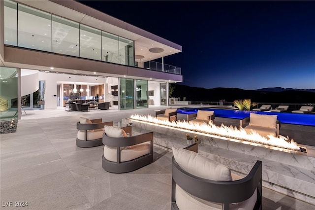 pool at twilight featuring an outdoor fire pit, a mountain view, and an outdoor pool