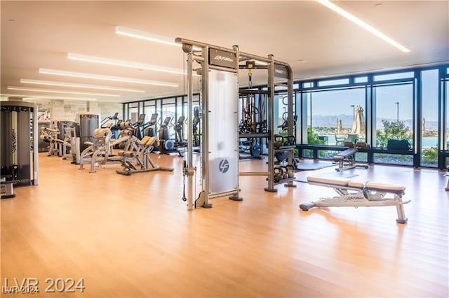 exercise room with a wall of windows and wood finished floors