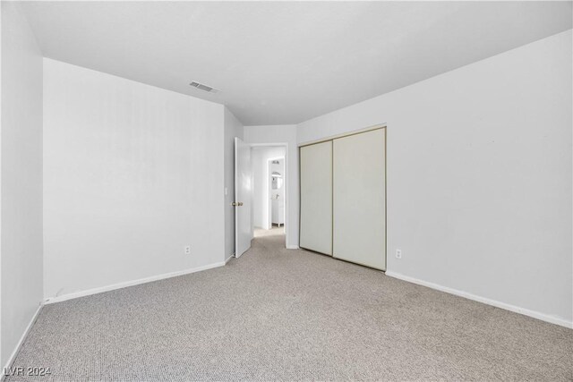 unfurnished bedroom featuring light colored carpet and a closet