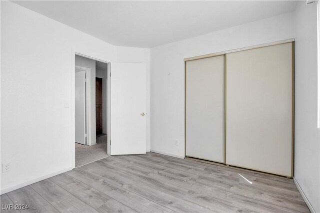 unfurnished bedroom featuring a closet and light hardwood / wood-style floors