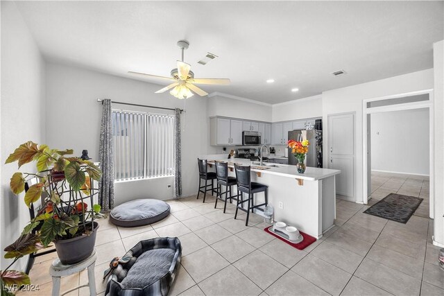 kitchen with appliances with stainless steel finishes, gray cabinetry, a breakfast bar, kitchen peninsula, and ceiling fan