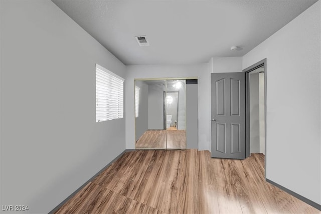 unfurnished bedroom with light hardwood / wood-style flooring and a closet