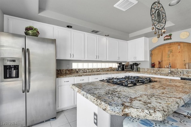 kitchen with black gas cooktop, a center island, light stone countertops, white cabinetry, and stainless steel refrigerator with ice dispenser